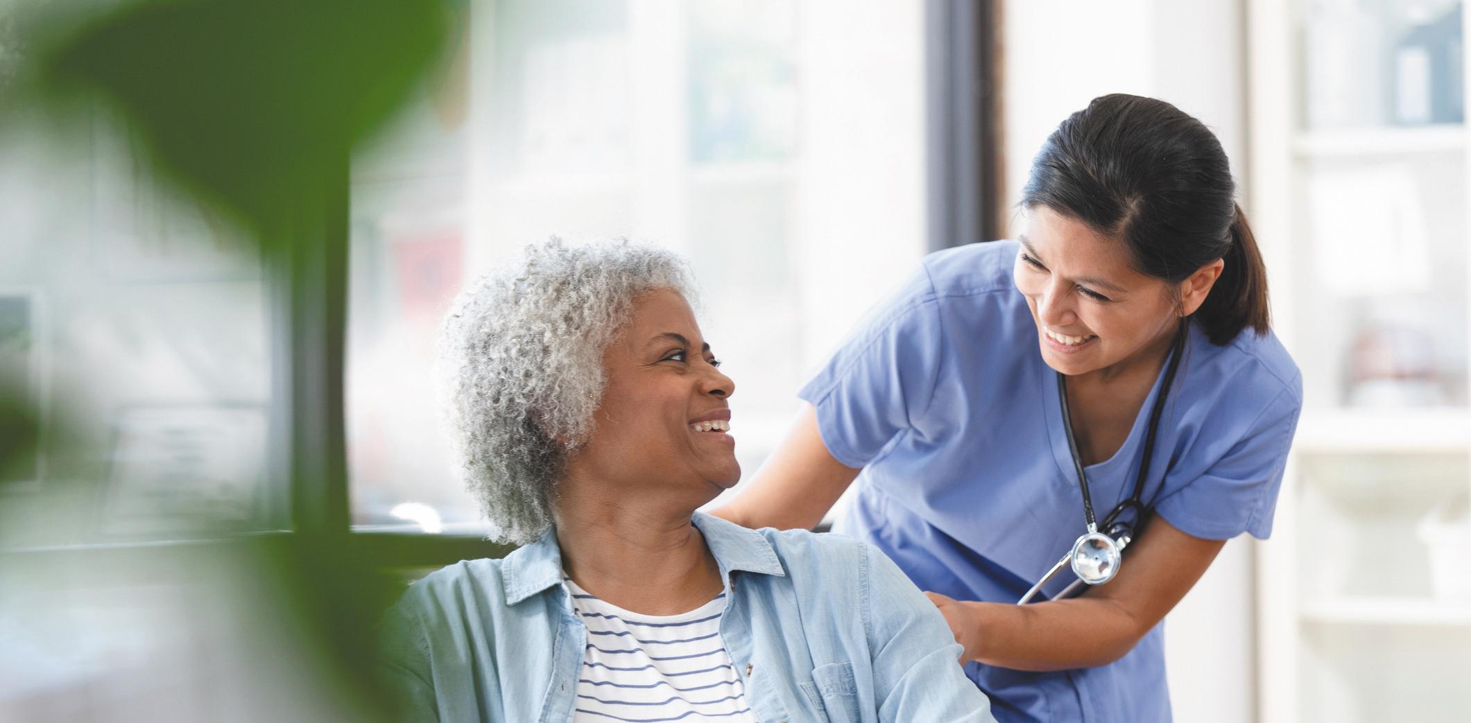 A healthcare worker smiles with an older woman.